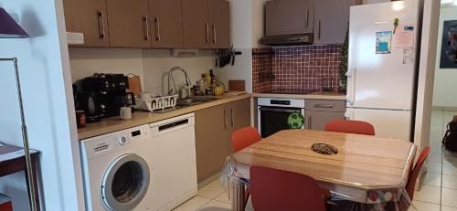 une cuisine avec une table et un réfrigérateur blanc dans l'établissement Appartement du port, à Sète