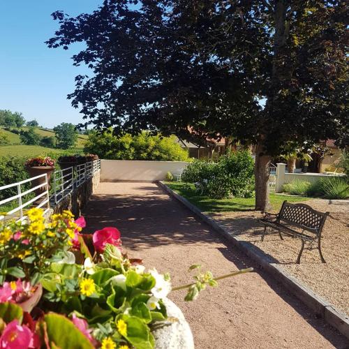 a bench sitting under a tree next to a bunch of flowers at Gite de la Réserve in Coublanc
