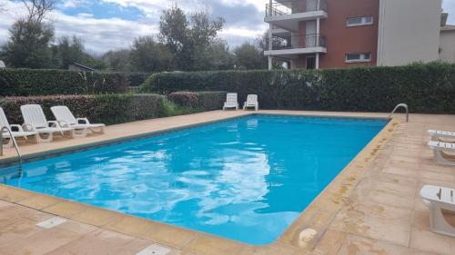 une piscine avec des chaises et un bâtiment dans l'établissement Appartement T3 piscine-Acces direct plage - Marseillan Plage, à La Celle-sous-Gouzon
