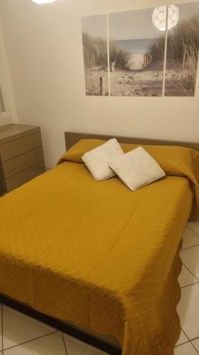 - un lit jaune avec 2 serviettes dans l'établissement Appartement T3 piscine-Acces direct plage - Marseillan Plage, à La Celle-sous-Gouzon