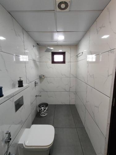 a white bathroom with a toilet and a window at Live On Cloud 9 at Kochi in Kakkanad