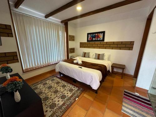 a bedroom with a bed and a large window at Hotel Pliosaurio Campestre in Villa de Leyva