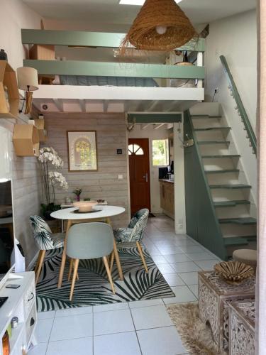 une salle à manger avec une table et un escalier dans l'établissement JOLIE MAISON AU GOLF, à Lacanau-Océan