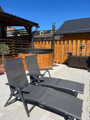 two lounge chairs on a patio with a wooden fence at Resort Biela Skala - CHATA Chopok Jasná Juh in Bystrá