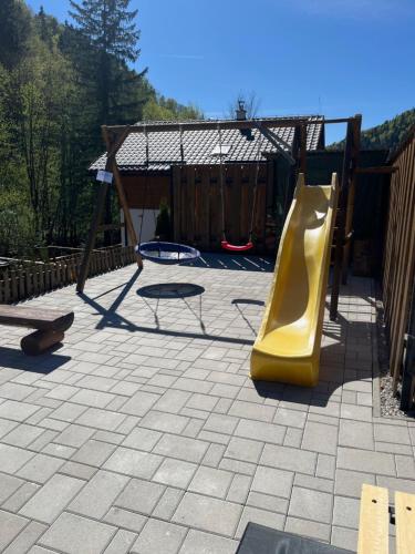a playground with a yellow slide and a swing at Resort Biela Skala - CHATA Chopok Jasná Juh in Bystrá