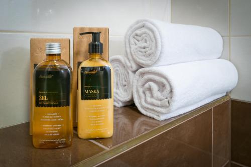 two bottles of shampoo and towels on a counter with towels at Piaskowy Brzeg in Jarosławiec