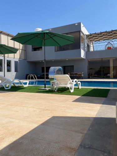 a house with a pool and a green umbrella at Yaras villa in Ash Shāghūr