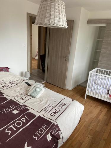 - une chambre avec un lit, un lit bébé et un lustre dans l'établissement Le gîte des vosges, à Anould
