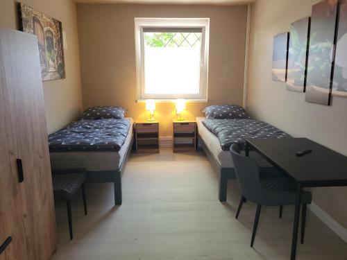 a room with two beds and a desk and a window at HK-Vermietung in Brieselang