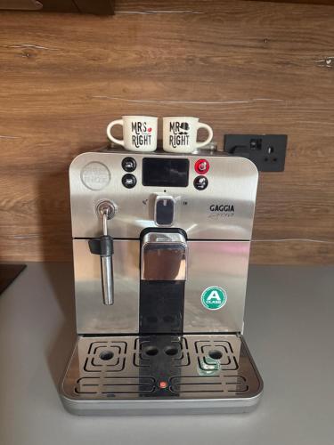 a silver coffee maker with two cups on it at New built cosy apartment within walking distance of Churchill Hospital in Oxford