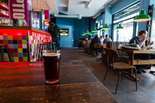 a glass of beer sitting on a wooden table in a restaurant at Copenhagen Downtown Hostel in Copenhagen