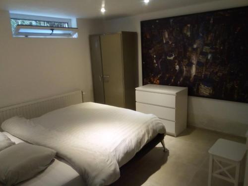 a bedroom with a bed and a dresser and a painting at relaxation in Waterloo, 2 steps from the center of Brussels in Waterloo