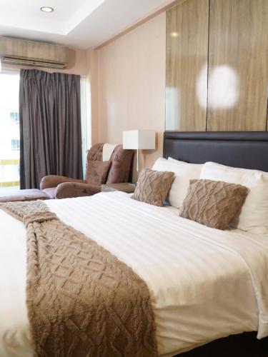 a large white bed in a room with a couch at Maya Residence in Pattaya South