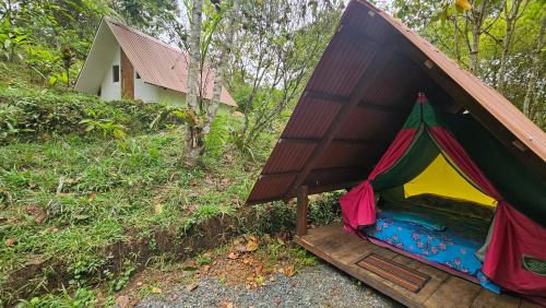 a tent in the woods next to a house at Glamping Montaña de Sueños in Cali
