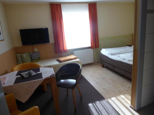 a small hotel room with a bed and a table and a chair at Landhotel Auerose Garni in Neu Kosenow