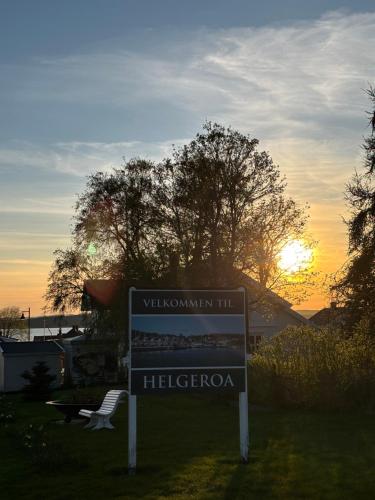 a sign in the grass with the sunset in the background at Brygga i Helgeroa in Larvik