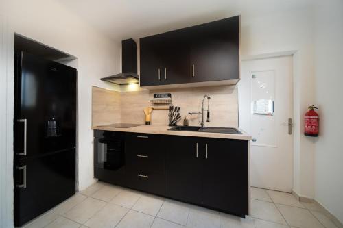 - une cuisine avec des placards noirs et un évier dans l'établissement Appartement tout équipé 6 à 8 couchages avec terrasse et parking, à Marseille