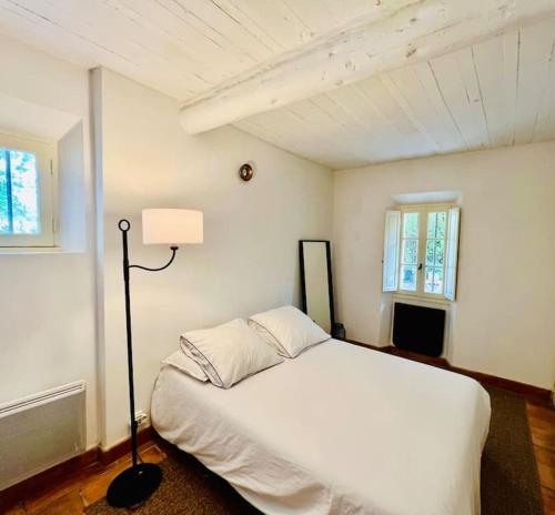 une chambre avec un lit blanc et une lampe dans l'établissement Villa climatisée avec piscine, à Gordes