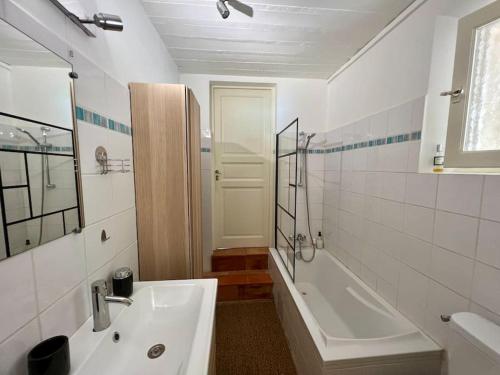 La salle de bains blanche est pourvue d'un lavabo, d'une baignoire et d'une douche. dans l'établissement Villa climatisée avec piscine, à Gordes