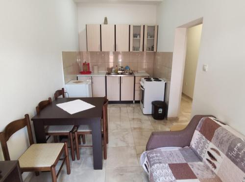 a living room with a table and a kitchen at Apartman Relax in Bijela
