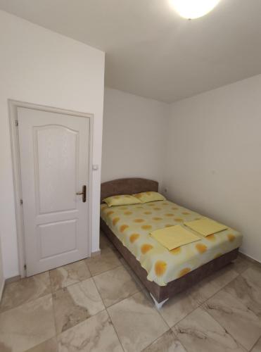 a bed sitting in a room next to a door at Apartman Relax in Bijela