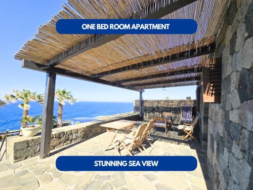 a pergola on a patio overlooking the ocean at Dammuso - Cala Cinque Denti - AFFITTICA in Pantelleria