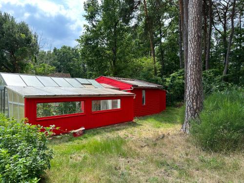 a red cabin with a silver roof next to a tree at Chambre pour 2 personnes, forêt, piscine in Arbonne-la-Foret