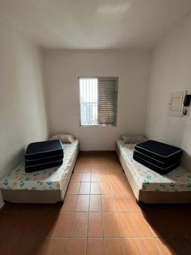 two beds sitting in a room with a window at Apartamento São Vicente in São Vicente