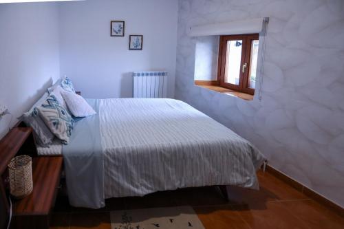 a white bedroom with a bed and a window at La casita de Elizabeth in San Martín de Unx
