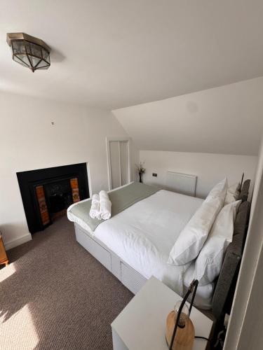 a bedroom with a white bed and a fireplace at Seaforth Cottage -Dog friendly, Historical Fishertown, central location in Nairn