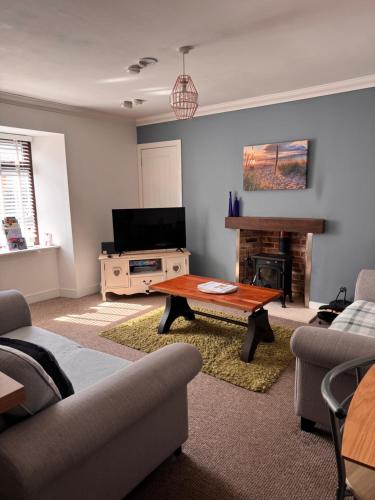 a living room with a couch and a table and a television at Seaforth Cottage -Dog friendly, Historical Fishertown, central location in Nairn