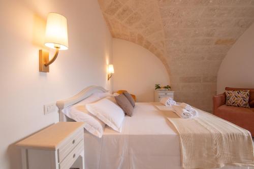 a bedroom with a large white bed and a chair at Masseria Galleppa by Apulia Hospitality in Monopoli