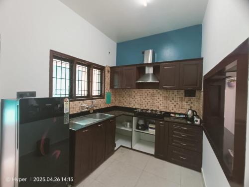 una cucina con armadi in legno e frigorifero nero di Danny's Villa-2 bedrooms with parking a Bangalore