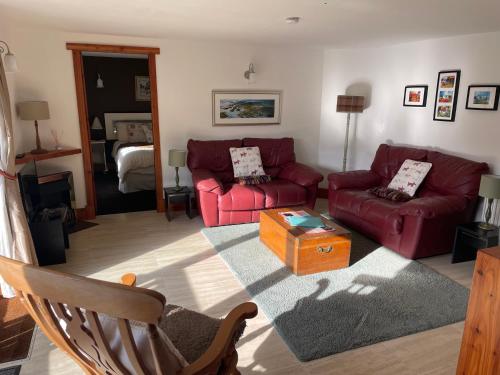 a living room with two red couches and a table at The Steading at Barmore in Tarbert