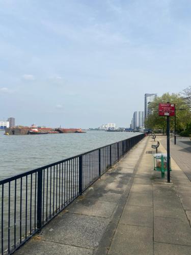 a sidewalk next to a body of water with a fence at Listed building close to River Thames in London