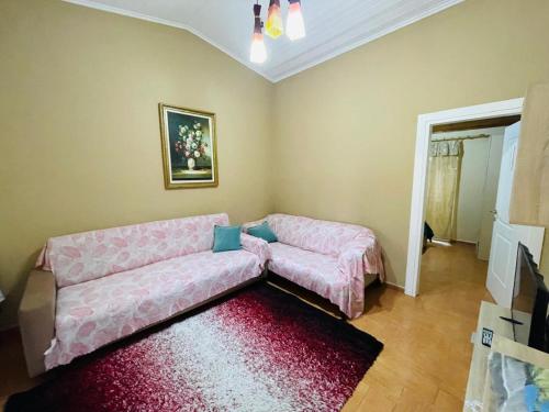 a living room with a pink couch and a red rug at Seaside Apartments Golem in Golem