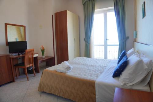a bedroom with a bed and a desk and a window at New Hotel Sonia in Santa Maria di Castellabate