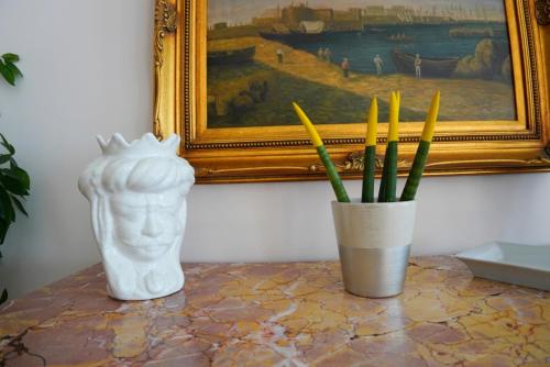 a vase and a statue on a table with a painting at New Hotel Sonia in Santa Maria di Castellabate