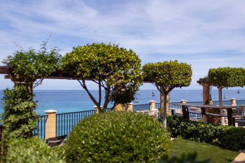 a view of the ocean from a park with trees at Hotel Rocca Della Sena in Tropea