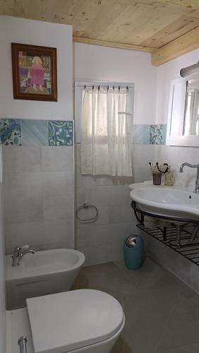 a bathroom with a white toilet and a sink at Le Mennule 26 in Alliste