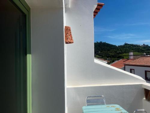 a white building with a chair on a balcony at Alojamento DOZE - Aldeia do Telheiro in Monsaraz