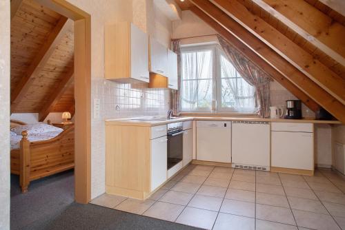 a kitchen with white cabinets and a window in a attic at Obst- und Ferienhof Lehle in Immenstaad am Bodensee