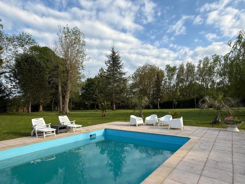 une piscine avec des chaises blanches et une terrasse dans l'établissement Escapade Romantique en Chalet Nature, Calme et Douceur au Bord de Marne, à Isles-lès-Villenoy