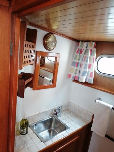 - une cuisine avec un évier et un miroir dans l'établissement Logement insolite, Péniche Hollandaise, à Cognac