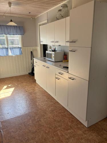 a kitchen with white cabinets and a microwave at Enkel sommarstuga OBS! Endast utedass in Gagnef