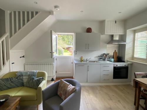 a kitchen with white cabinets and a couch in a room at The Garden House in Dewlish