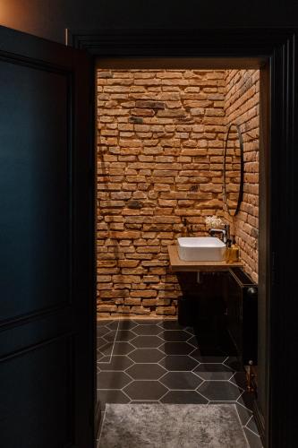 a bathroom with a sink and a brick wall at Black Princess in Cēsis