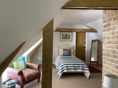 a bedroom with a bed and a chair in a attic at The Garden House in Dewlish