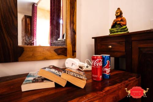 a wooden table with books and cans of cocacola at Hotel Golden Legacy - by PRAMANA EXP in Jaisalmer