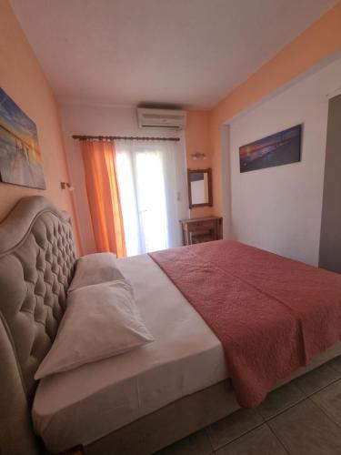 a bedroom with a bed with a red blanket and a window at Sun Ray Sivota 8 in Syvota